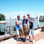 3 men displaying their fish catch