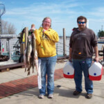 man and woman holding bait and fish