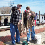 two men proudly showing their fish